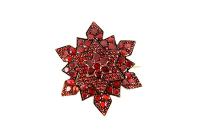 Lot 156 - A garnet multi-rayed star brooch, set with...