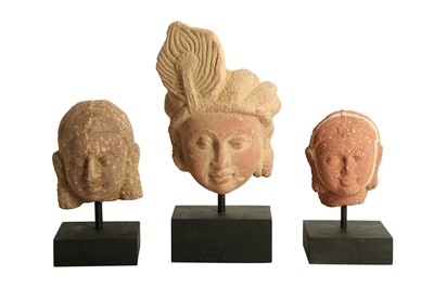 Lot 223 - THREE MOTTLED RED SANDSTONE CARVINGS OF YAKSHINI AND YAKSHA HEADS
