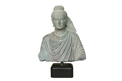 Lot 200 - A CARVED GRAY SCHIST BUST OF THE HISTORICAL BUDDHA, SIDDHARTHA GAUTAMA SHAKYAMUNI